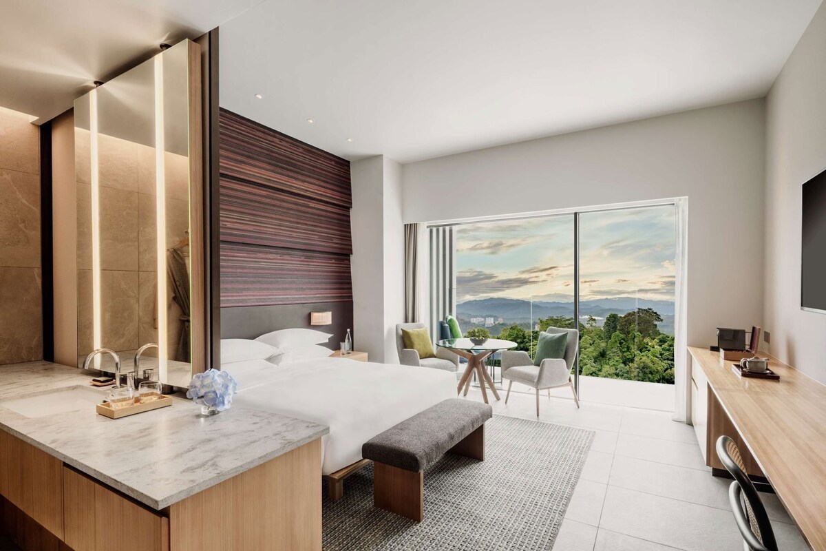 Una habitación de hotel moderna con una cama grande, un escritorio y vistas a las montañas.
