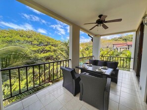 Enjoy dining al fresco on this balcony with a table set amidst lush surroundings.
