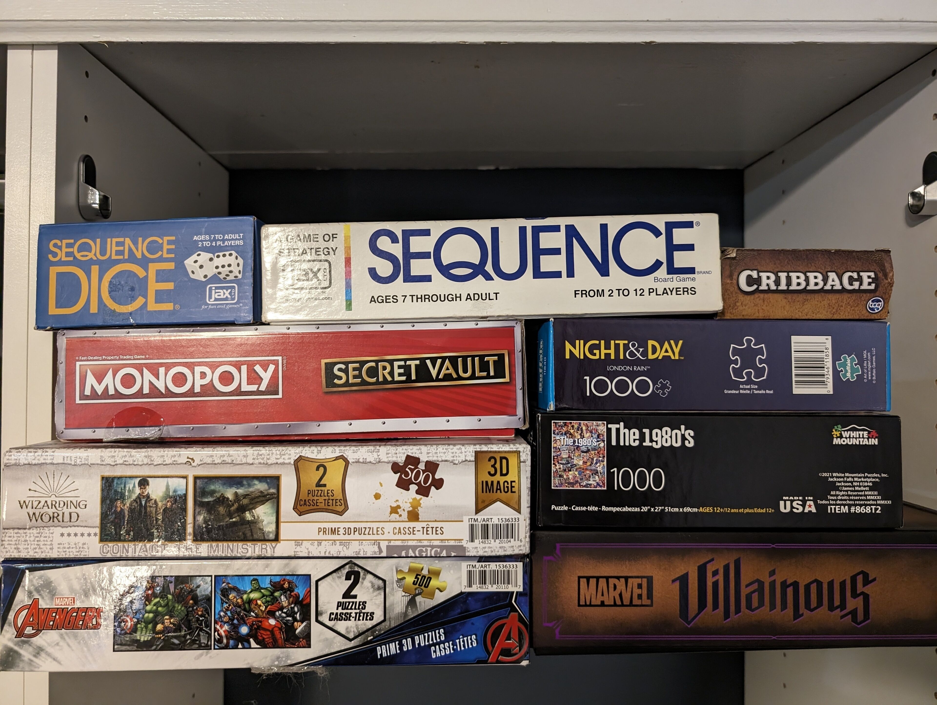 Uma coleção de jogos de tabuleiro empilhados num armário.