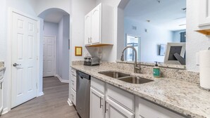 A modern kitchen with granite countertops, stainless steel appliances, and white cabinetry. - 2788 Windsor Hills (Kissimmee)