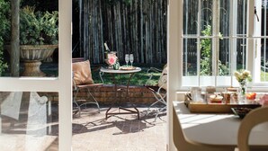 A patio with a table set for two, a wooden fence, and a potted plant. - VILLA PUCCINI (Cape Town)