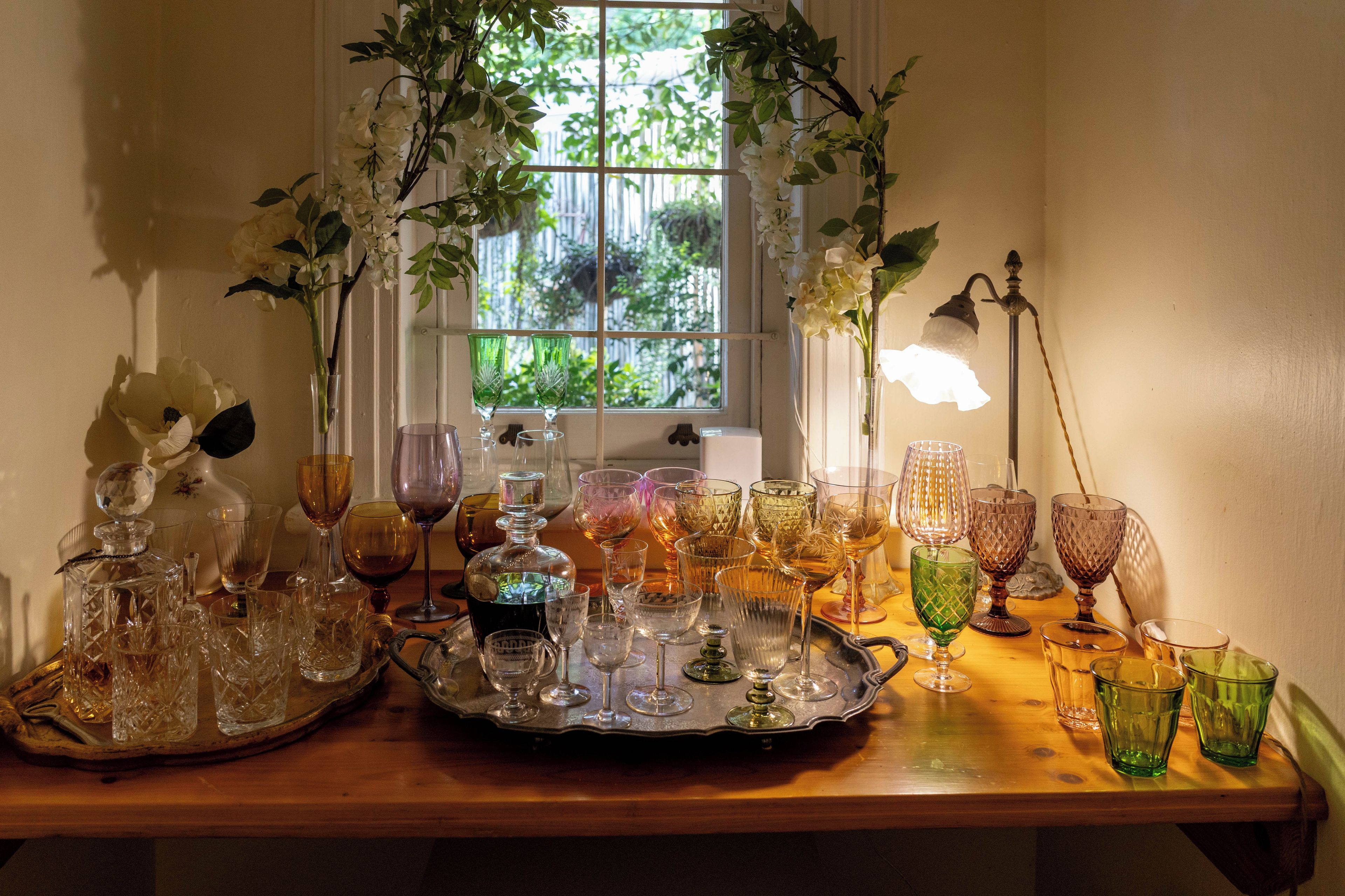 A table with various glassware and a window with a view of greenery.
