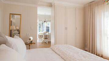 A bedroom with a large bed, a desk, and a wardrobe.