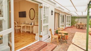 An open-plan living area with a wooden floor, a dining table with chairs, a TV, and a large mirror. - VILLA PUCCINI (Cape Town)