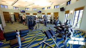 A gym with various exercise machines, a patterned carpet, and large windows allowing natural light. - 1414 Champions Gate (Davenport)