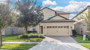 A two-story house with a beige facade, a tiled roof, and a garage. - 1414 Champions Gate (Davenport)