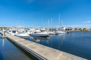 A marina with multiple boats docked, a concrete dock, and buildings in the background.