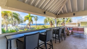 A covered outdoor seating area with a view of the beach and palm trees. - 301 Little Harbor Inn (Ruskin)