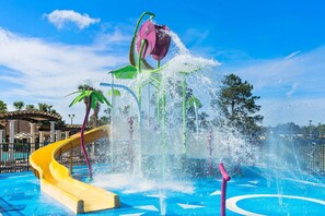 A water park with a yellow slide, water jets, and palm trees. - 2821 Windsor Hills (Kissimmee)
