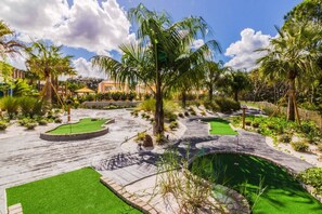 Stroll through a serene outdoor space surrounded by lush landscaping, palm trees, a small water feature, and a winding pathway.