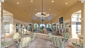 A spacious indoor area with striped chairs and tables, a ceiling fan, and a view of the outside. - 7812 Windsor Hills (Kissimmee)