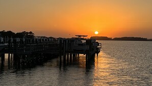 A pier extending into calm water with a sunset in the background. - Stunning River Views-Easy Walk to Beach & Shops-Pool and Day dock!-3BR Townhome (Folly Beach)