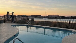A swimming pool with a metal ladder, surrounded by a fence, and a view of buildings in the background. - Stunning River Views-Easy Walk to Beach & Shops-Pool and Day dock!-3BR Townhome (Folly Beach)