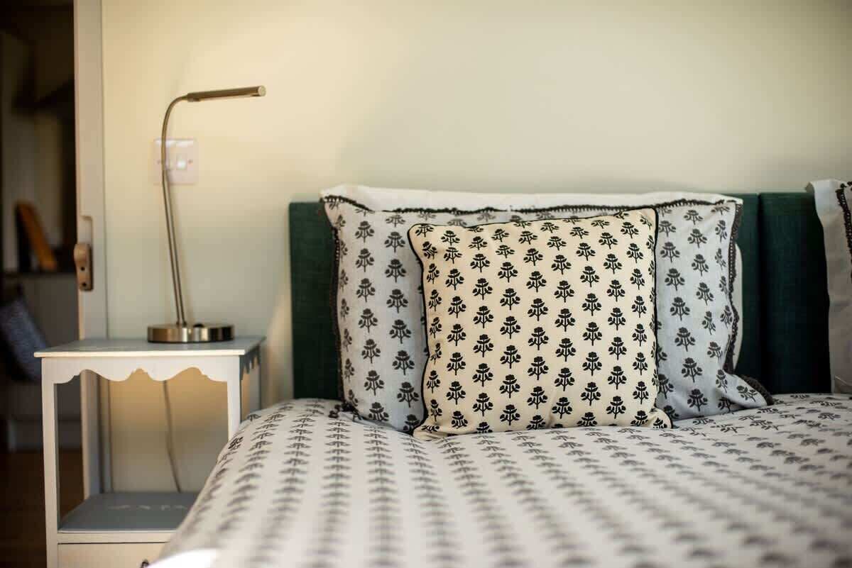 A neatly made bed with patterned bedding, a bedside lamp, and a small bedside table.