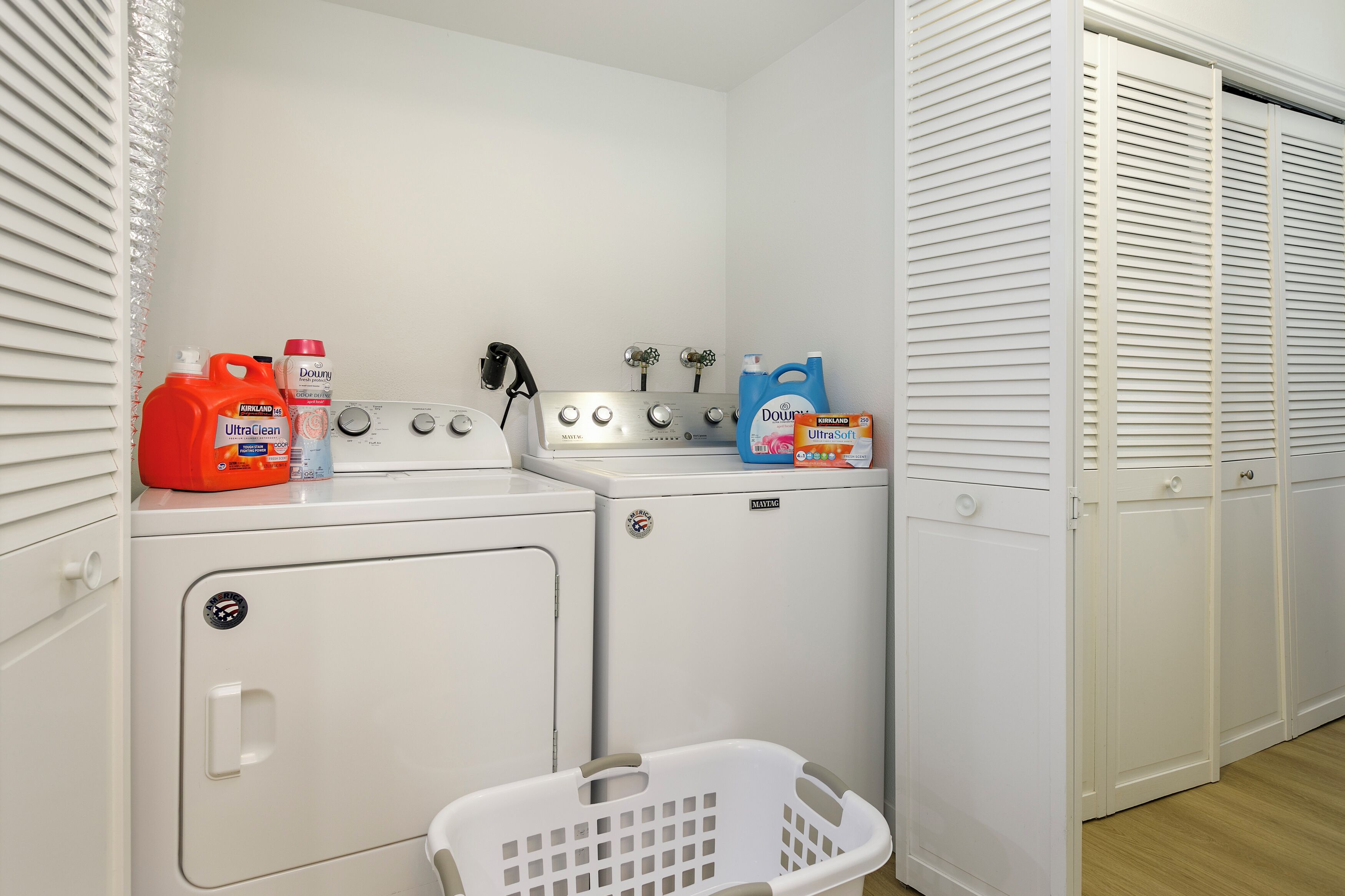 Un espace buanderie équipé de deux machines à laver, d’un sèche-linge et d’un panier à linge.