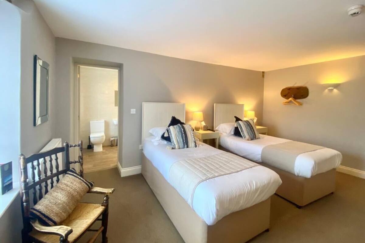 A hotel room with two beds, a bench, and a mirror.