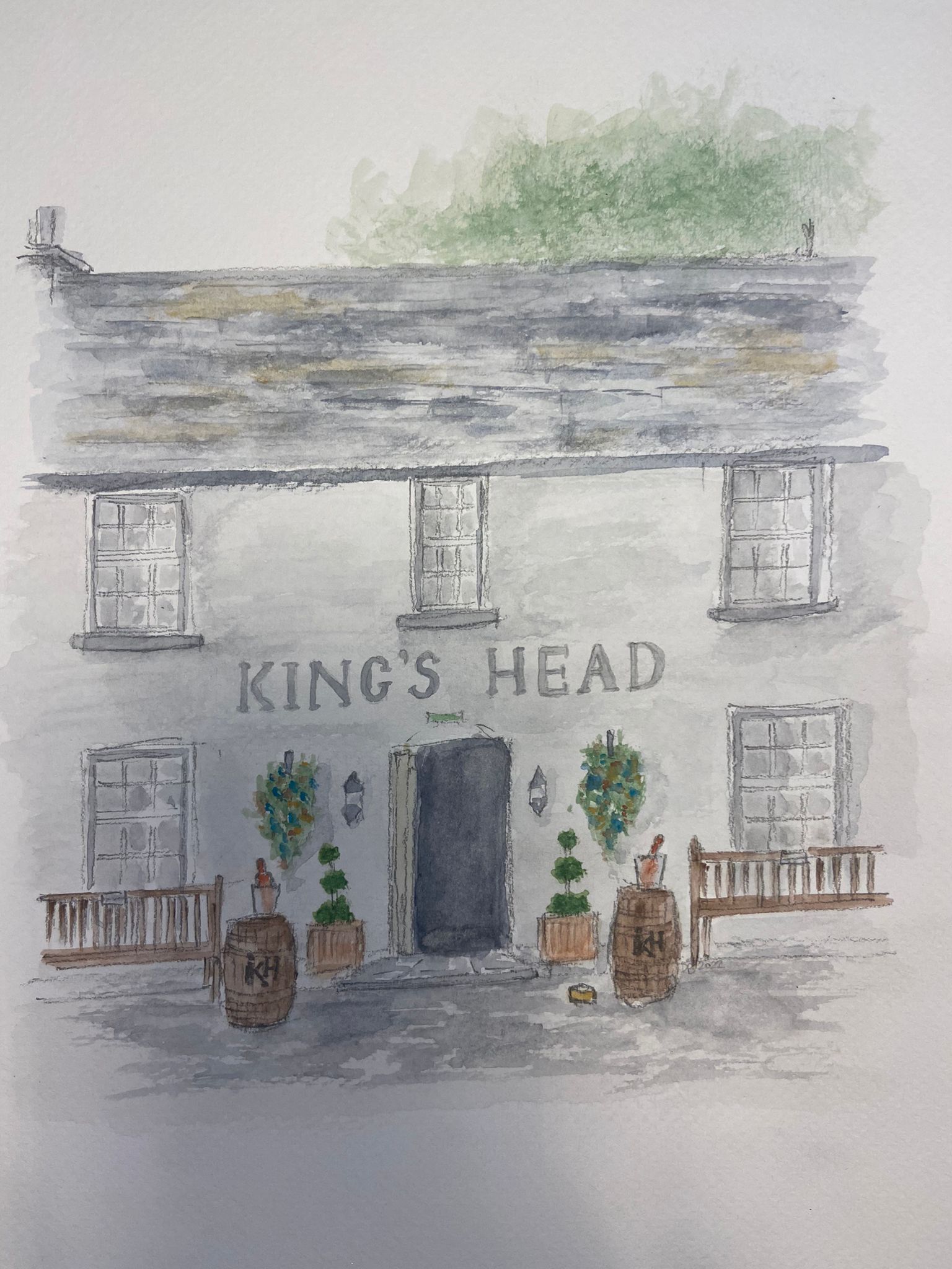 A building with the sign "King's Head" above the entrance. There are four windows on the facade, a door, and two small potted plants in front.