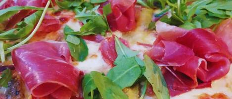 A pizza topped with arugula and prosciutto.