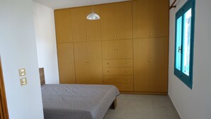 A bedroom with a bed, wooden wardrobe, and a window with blue trim.