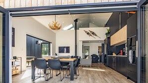 A modern kitchen with a large island, black cabinetry, and a built-in microwave. - Mangawhero River Chalet (Ohakune)