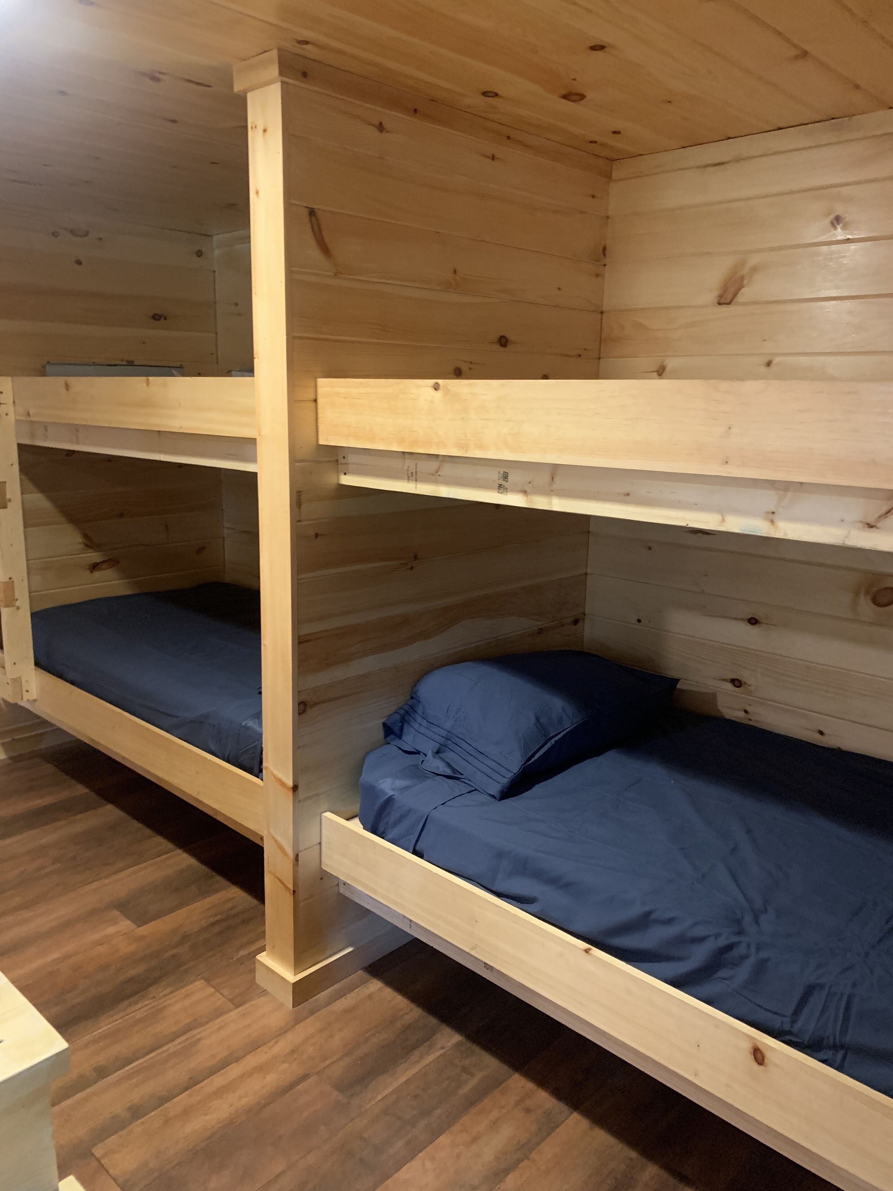 A bunk bed room with wooden walls and floors.