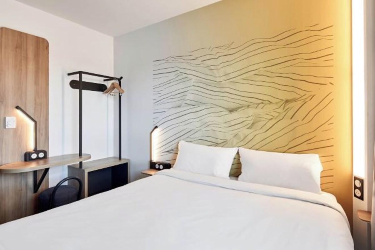 Una habitación de hotel moderna con una cama, un escritorio y una silla.