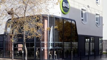Un hôtel de type « bed and breakfast » doté d’une façade moderne en verre, d’un espace restaurant bien visible et offrant une vue dégagée sur la rue.