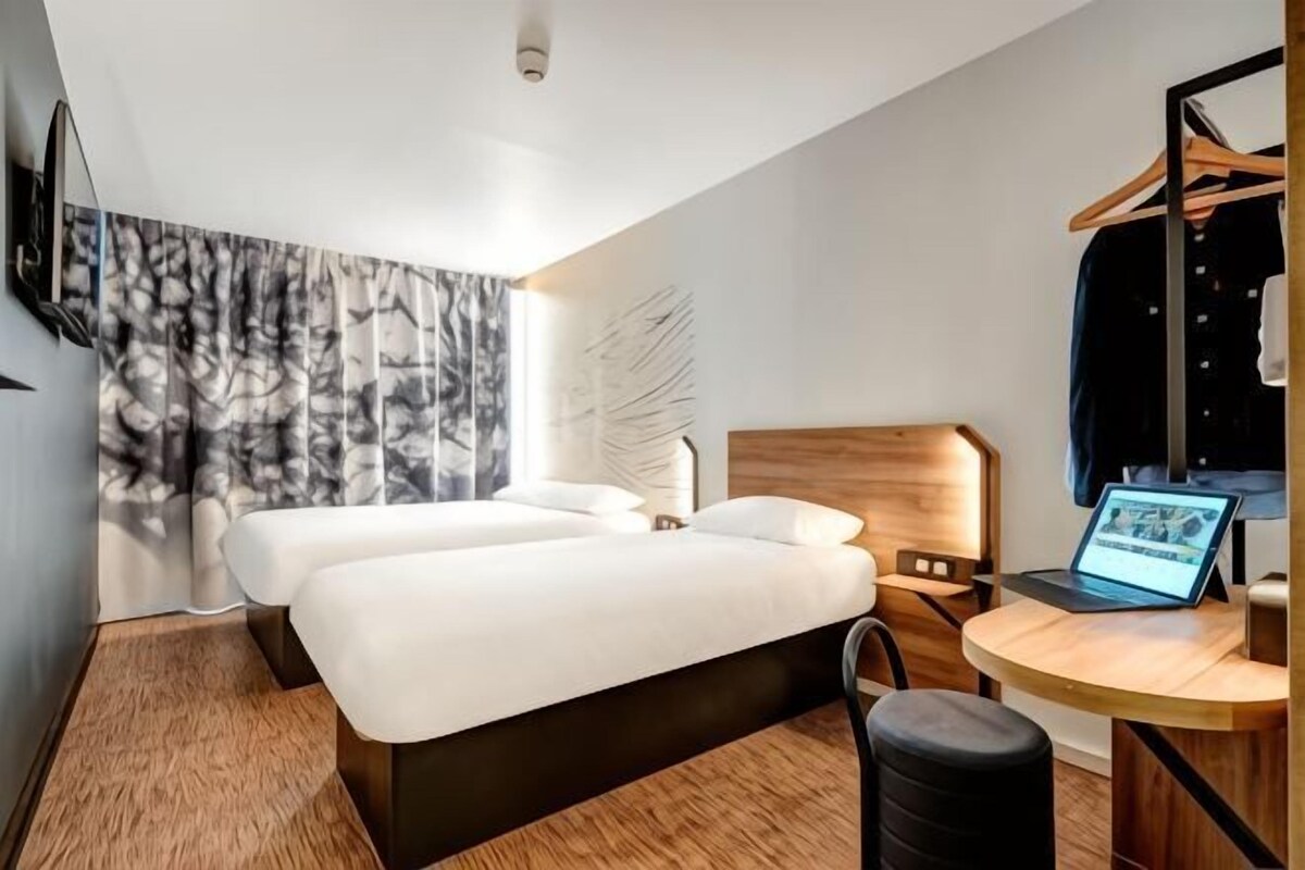 Una habitación de hotel moderna con una cama grande, un escritorio con una computadora portátil y un espejo.
