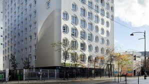 A modern building with a unique facade featuring circular windows and a curved section. - B&B HOTEL Paris Ivry Quai de Seine (Ivry-sur-Seine)