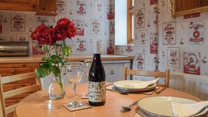 Ein Esstisch mit einer Weinflasche, einem Glas und einer Vase mit roten Rosen.