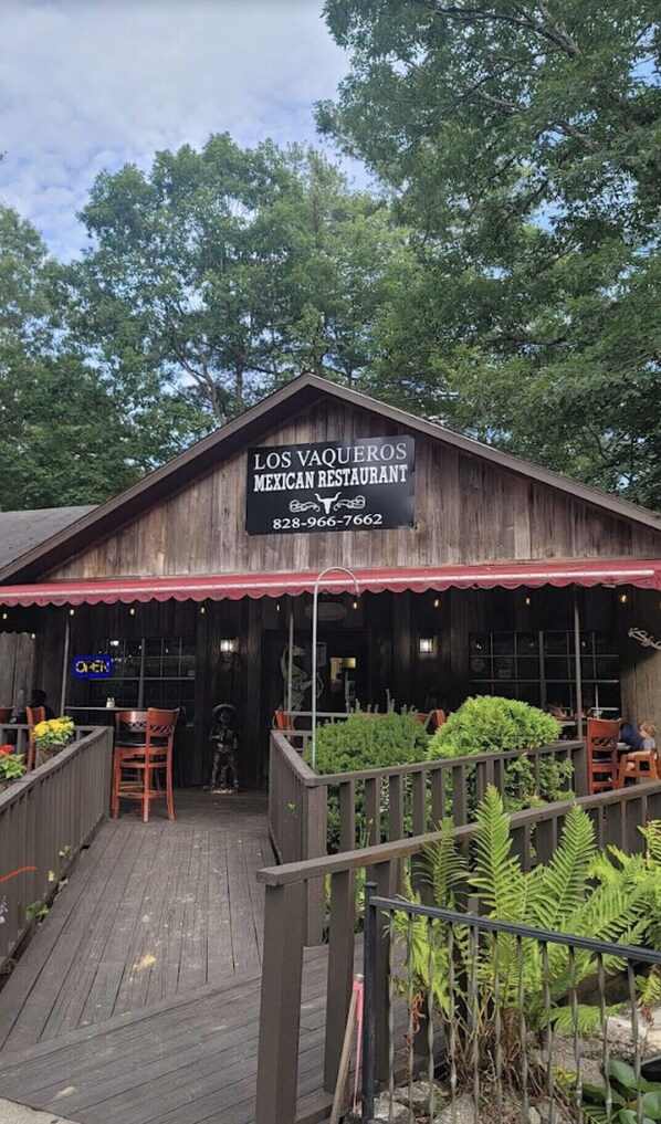 Un bâtiment en bois avec une enseigne indiquant « Los Vaqueros, restaurant mexicain » et un numéro de téléphone.