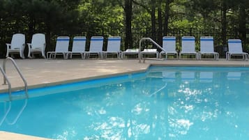 Relax by the pool surrounded by shaded trees and lounge chairs.