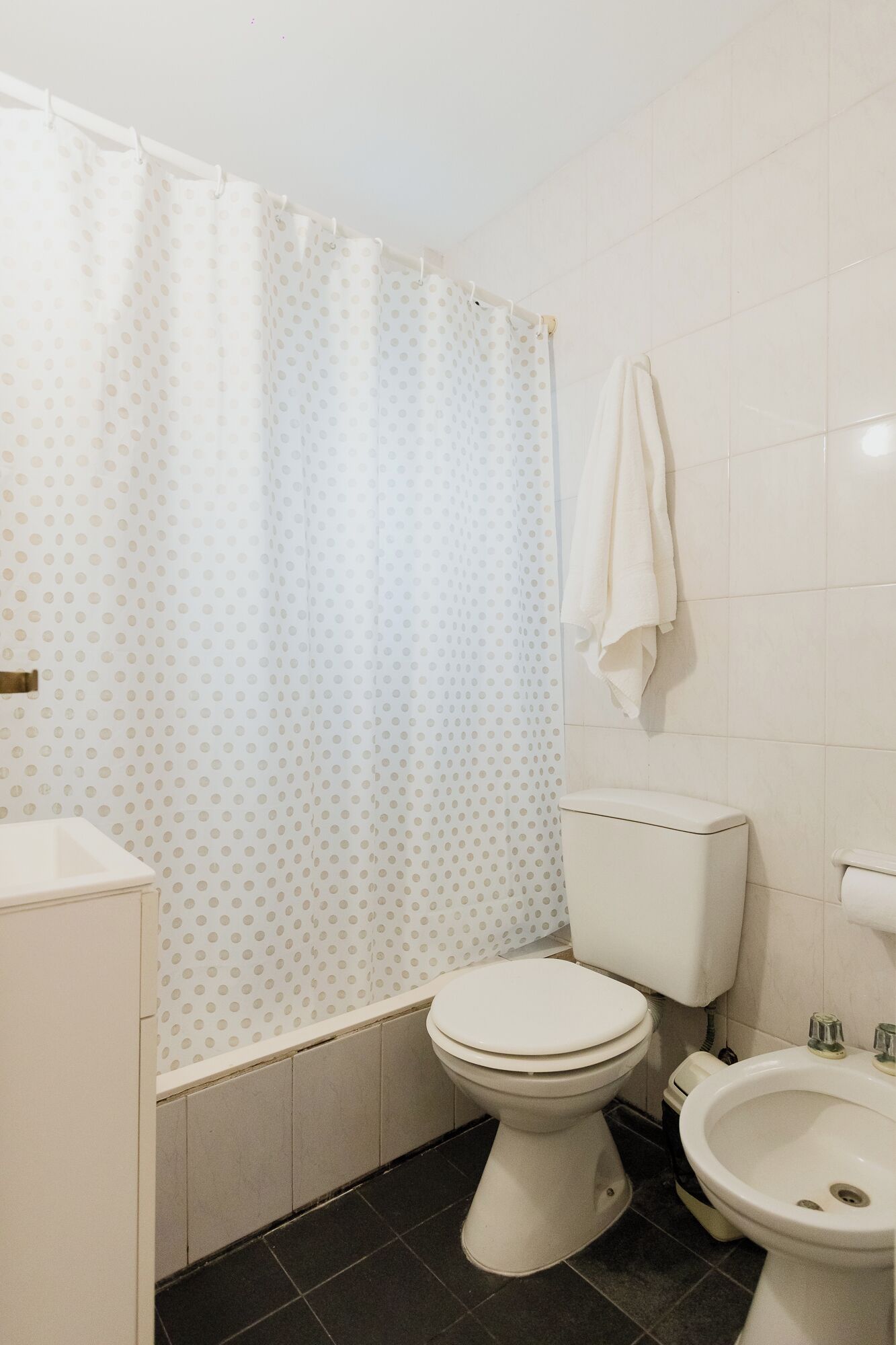Un baño con inodoro, bidé y cortina de ducha con estampado de lunares.