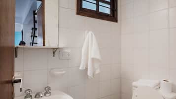 Un baño pequeño con un lavamanos blanco, un espejo, una ventana y un inodoro.