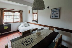 A room with a bed, a table with a fish-patterned placemat, a wicker lamp, and a framed fish picture on the wall.