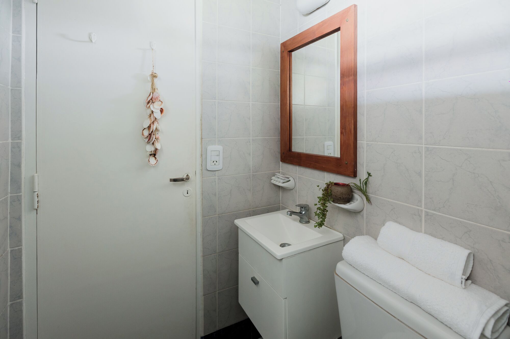 A bathroom with a white sink, a wooden-framed mirror, and a towel rack.