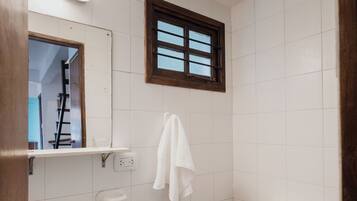 A small, clean bathroom with a white sink, a toilet, and a window with blinds.