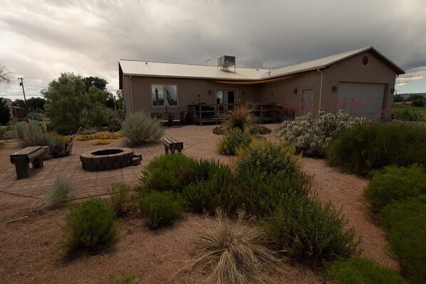 A modern house with a patio area, outdoor seating, and a fire pit.