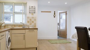 A modern kitchen with a built-in washing machine, a sink, and a window with blinds.