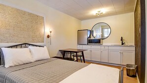 A bedroom with a bed, bedside table, wall-mounted light, and a small table with chairs. - Old Tale Inn (Leadville)