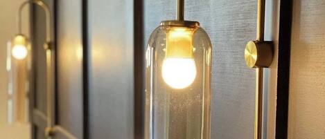 Una lámpara de pared con una carcasa de vidrio transparente y un brazo metálico curvo.