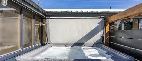 Un bain à remous doté d’une terrasse en bois et d’une rambarde en métal.