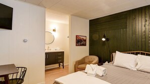 A bedroom with a bed, a chair, a desk, and a vanity with a mirror. - Old Tale Inn (Leadville)