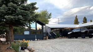 A gravel driveway leading to a building with a covered porch and a black pickup truck parked nearby. - Old Tale Inn (Leadville)