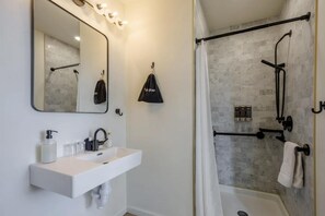 A modern bathroom with a white sink, a large mirror, and a shower area with a glass door.