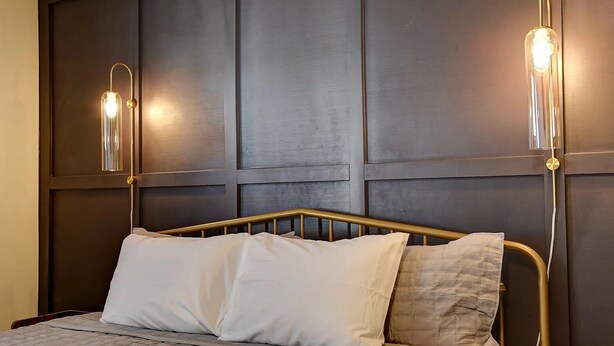 A bed with a metal frame and two bedside lamps with clear glass shades. - Old Tale Inn (Leadville)