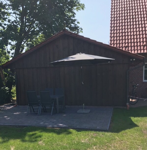 Un bâtiment en bois doté d’un patio couvert, d’une table et de chaises, et d’un vélo garé à l’extérieur.