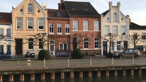 Una hilera de edificios tradicionales de estilo europeo a lo largo de un canal, bajo un cielo despejado.