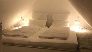 Un dormitorio acogedor en el ático con una cama, dos lámparas de noche y techo inclinado.