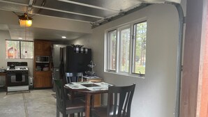Cocina compacta con comedor, que incluye refrigerador, estufa, microondas y ventana con vista al exterior.